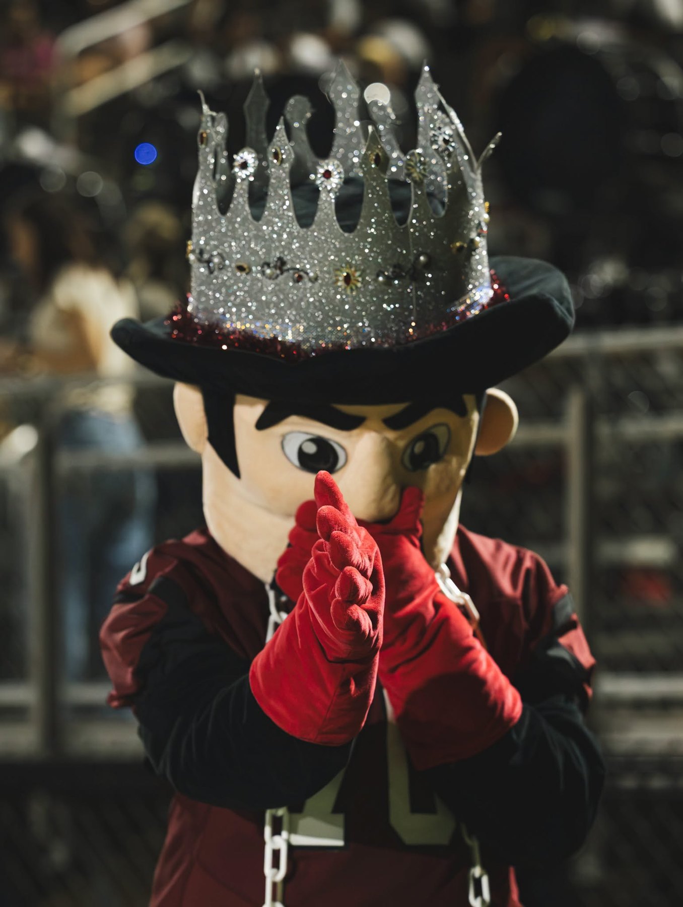 Caledonia's Cavalier mascot in a glittering crown, gloved hands pressed together