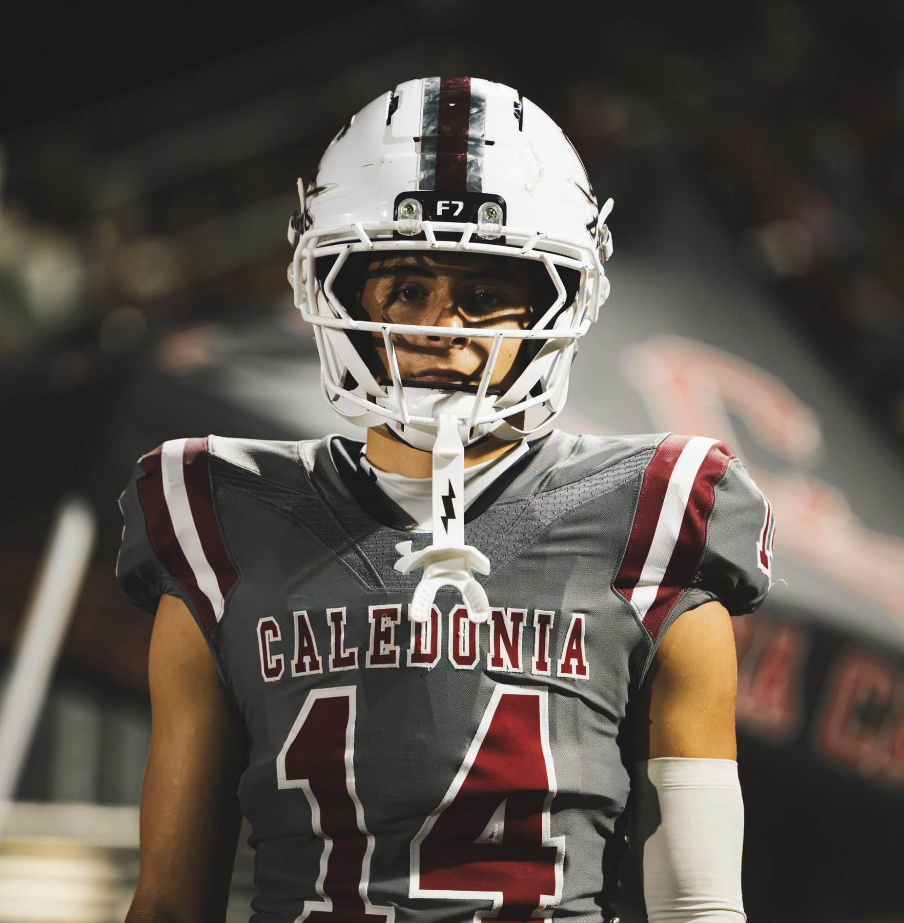 A Caledonia player stands, helmet on, under the lights