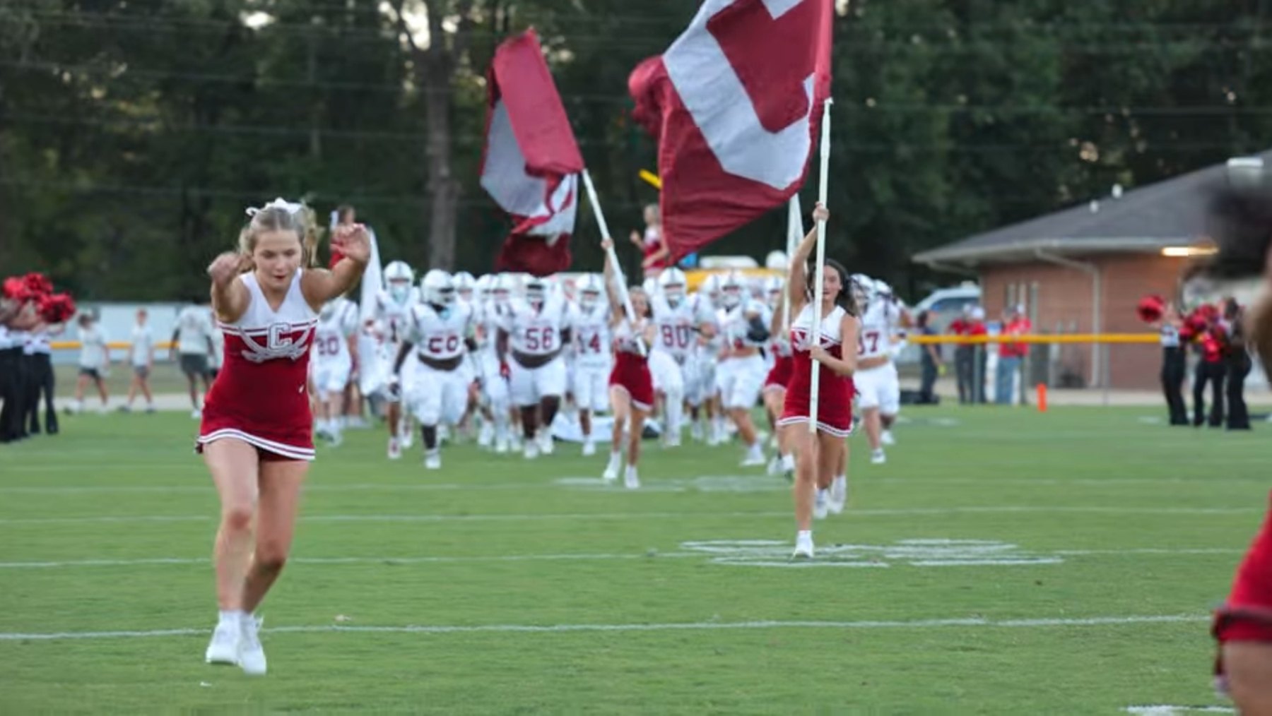 Caledonia's cheerleaders and flags lead the team onto the field
