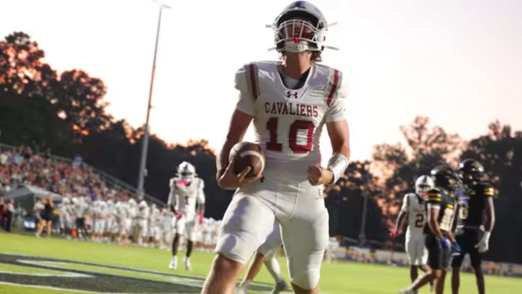 A Caledonia ball carrier runs under a sunset sky