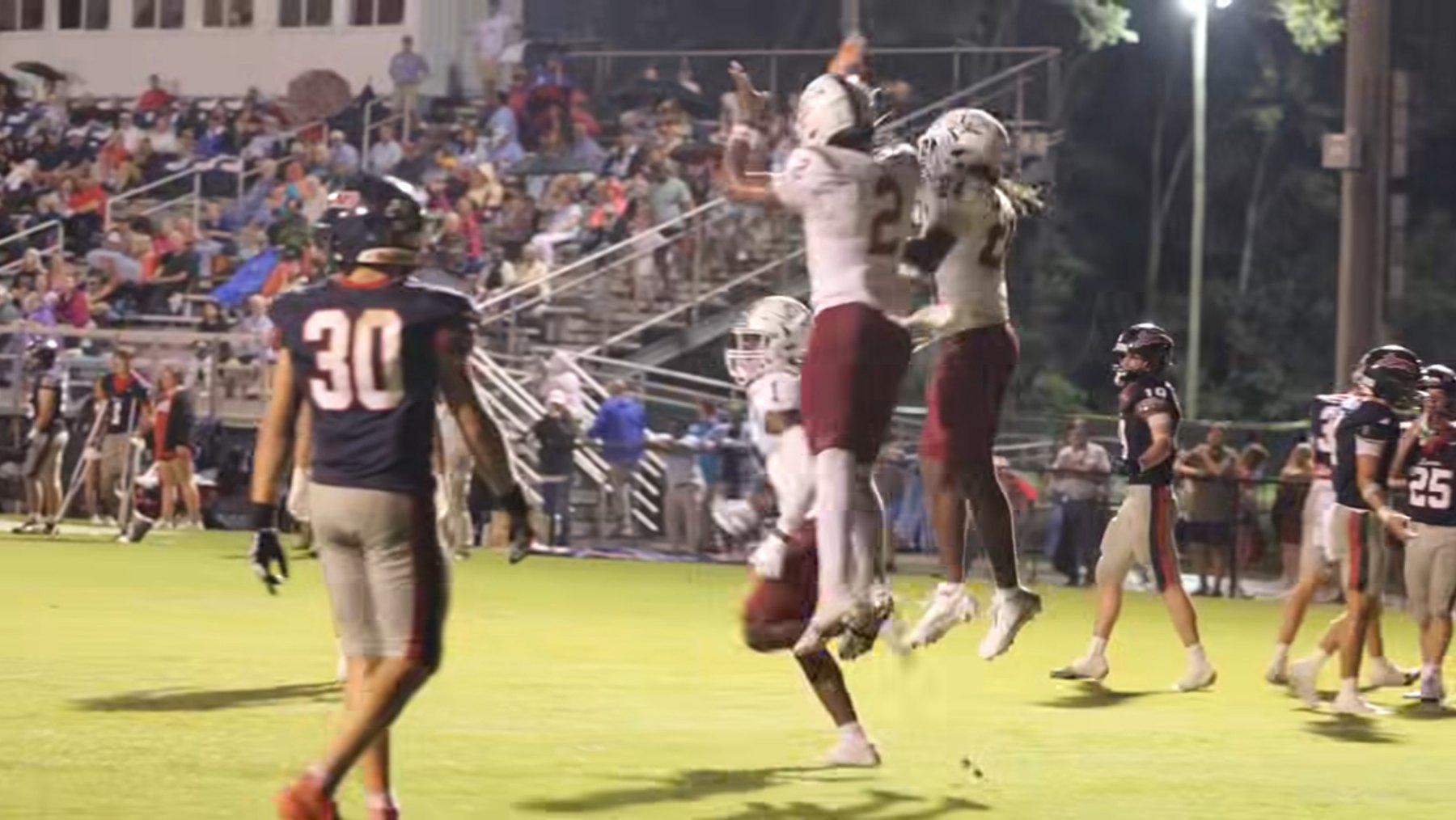 Two Caledonia players leap together to celebrate in front of the stands at Lamar