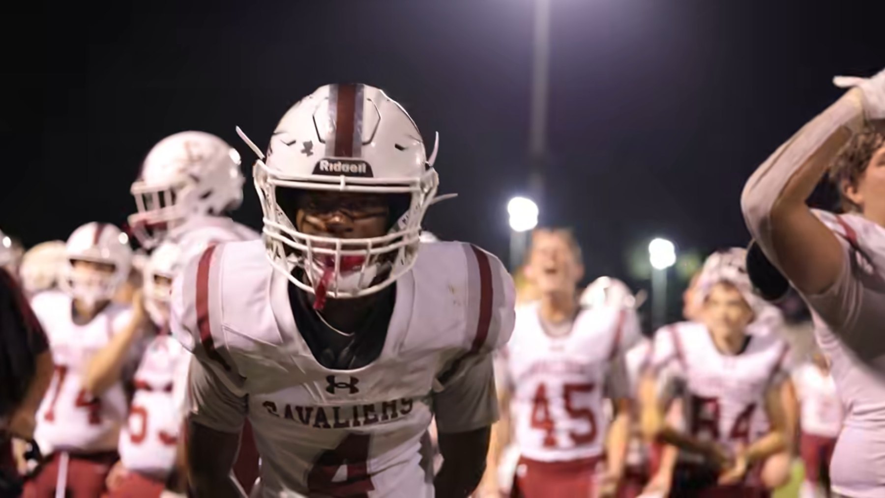 A Caledonia player stares into the camera as his teammates cheer behind him