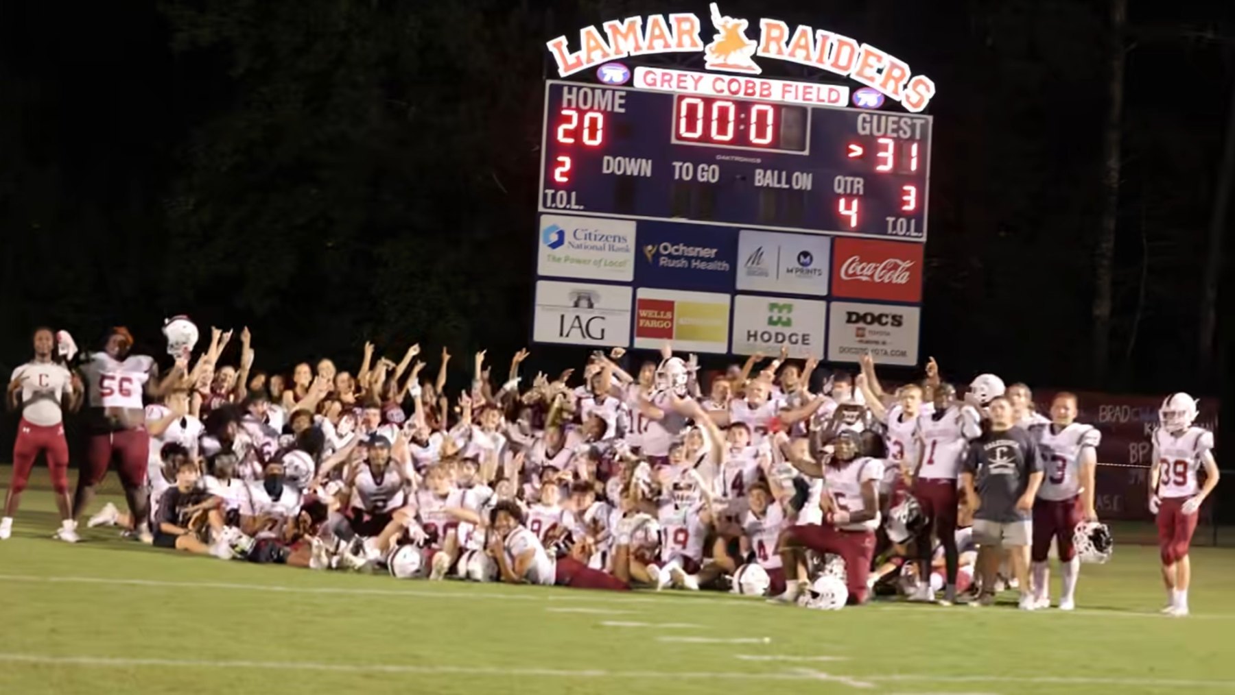 Caledonia's team celebrates on the field under Lamar's scoreboard after the final whistle